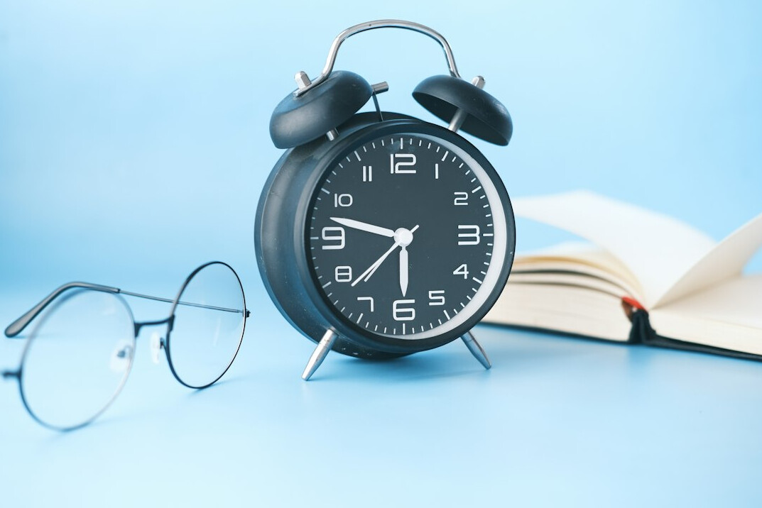 Stack of old books and a magnifying glass on a wooden desk